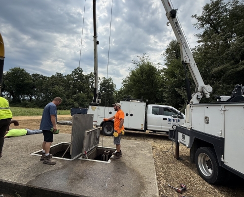 MVP service crew using a crane truck to lower equipment into a concrete vault